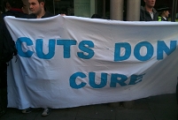 Demonstranten halten Transparent "Cuts Don't Cure"